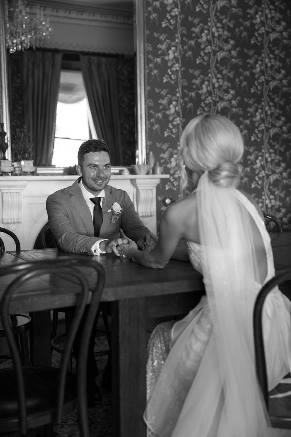 ash and andrew holding hands across the table at thei wallalong house wedding