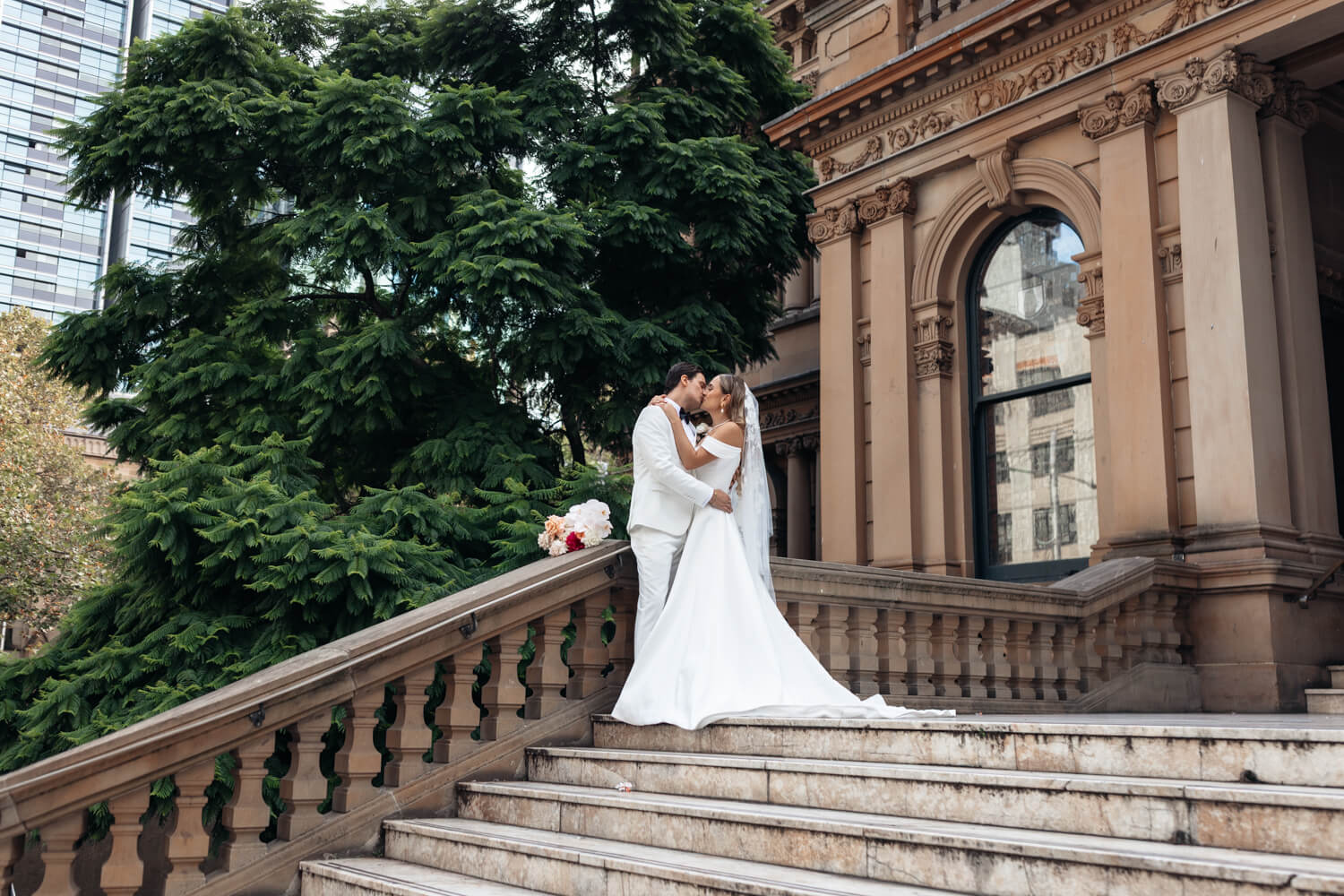 Bride and groom kissing on their wedding day n the Town Hall steps in Sydney