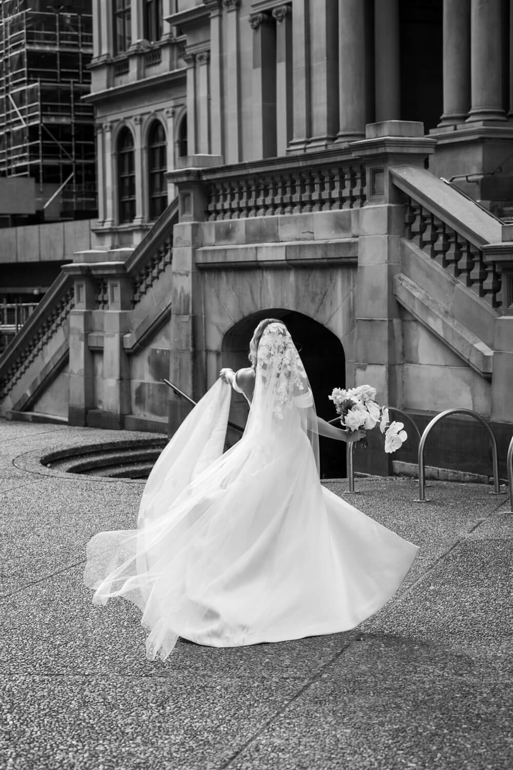 A portrait of the bride twirling with her dress outside Town Hall