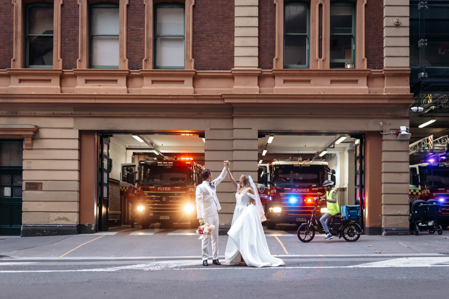 The bride and groom standing in front of the fire station outside their Events By Alpha wedding