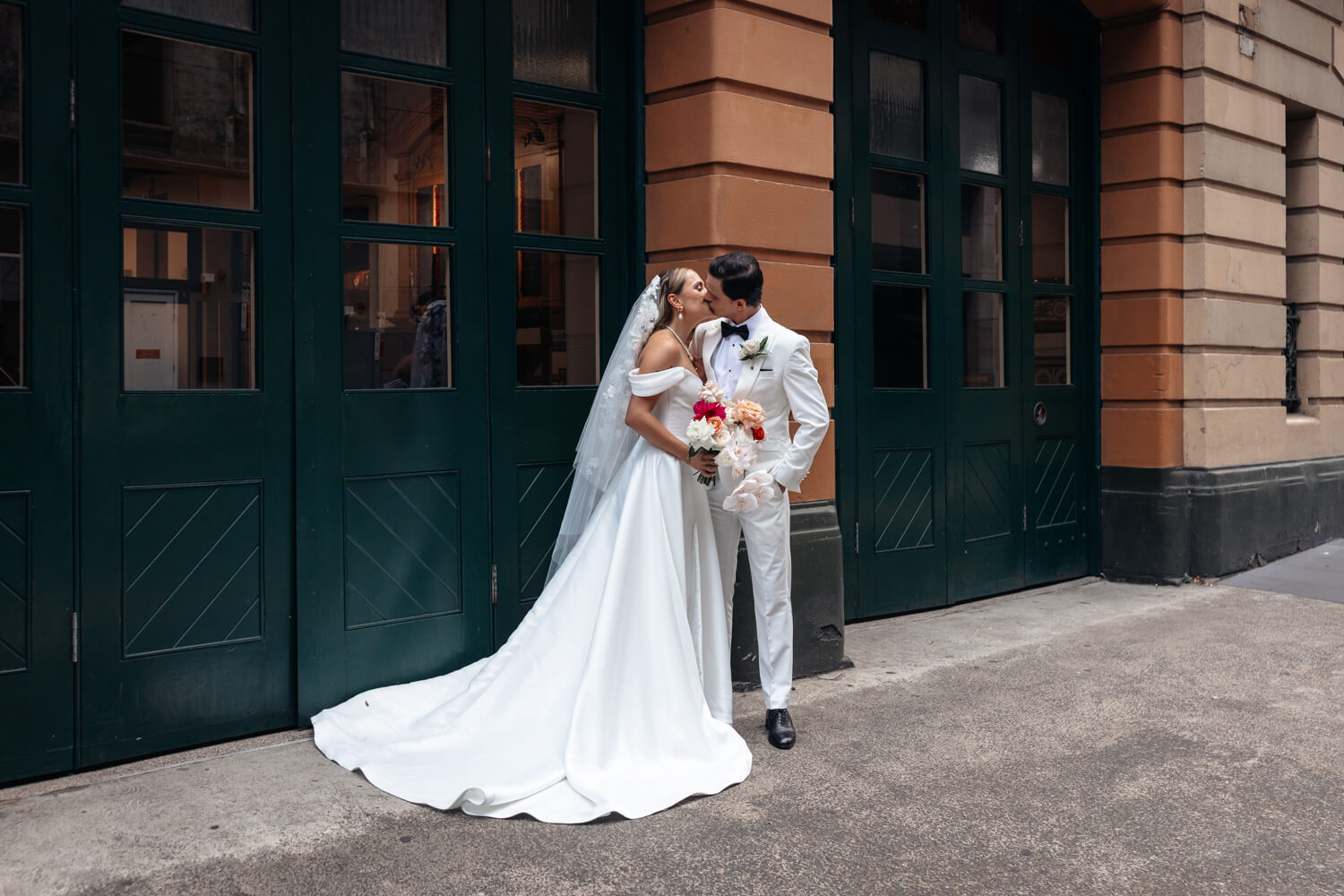 Bride and groom kissing outside the fire station across the road from Events By Alpha