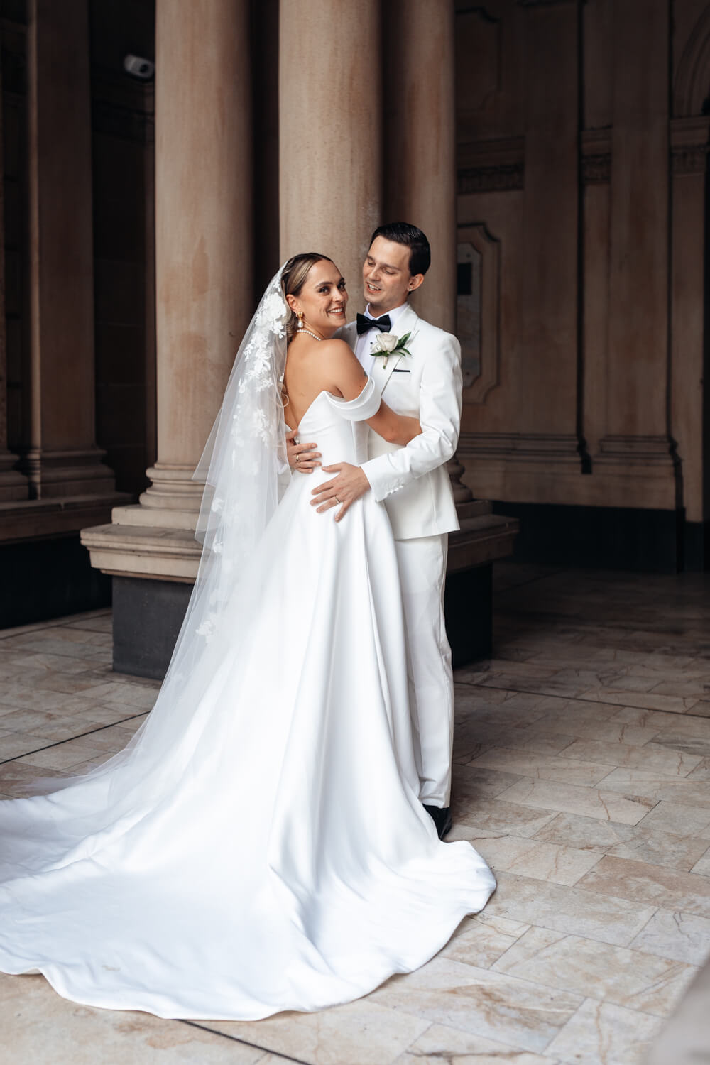 The bride and groom smiling at each other during their wedding at Town Hall