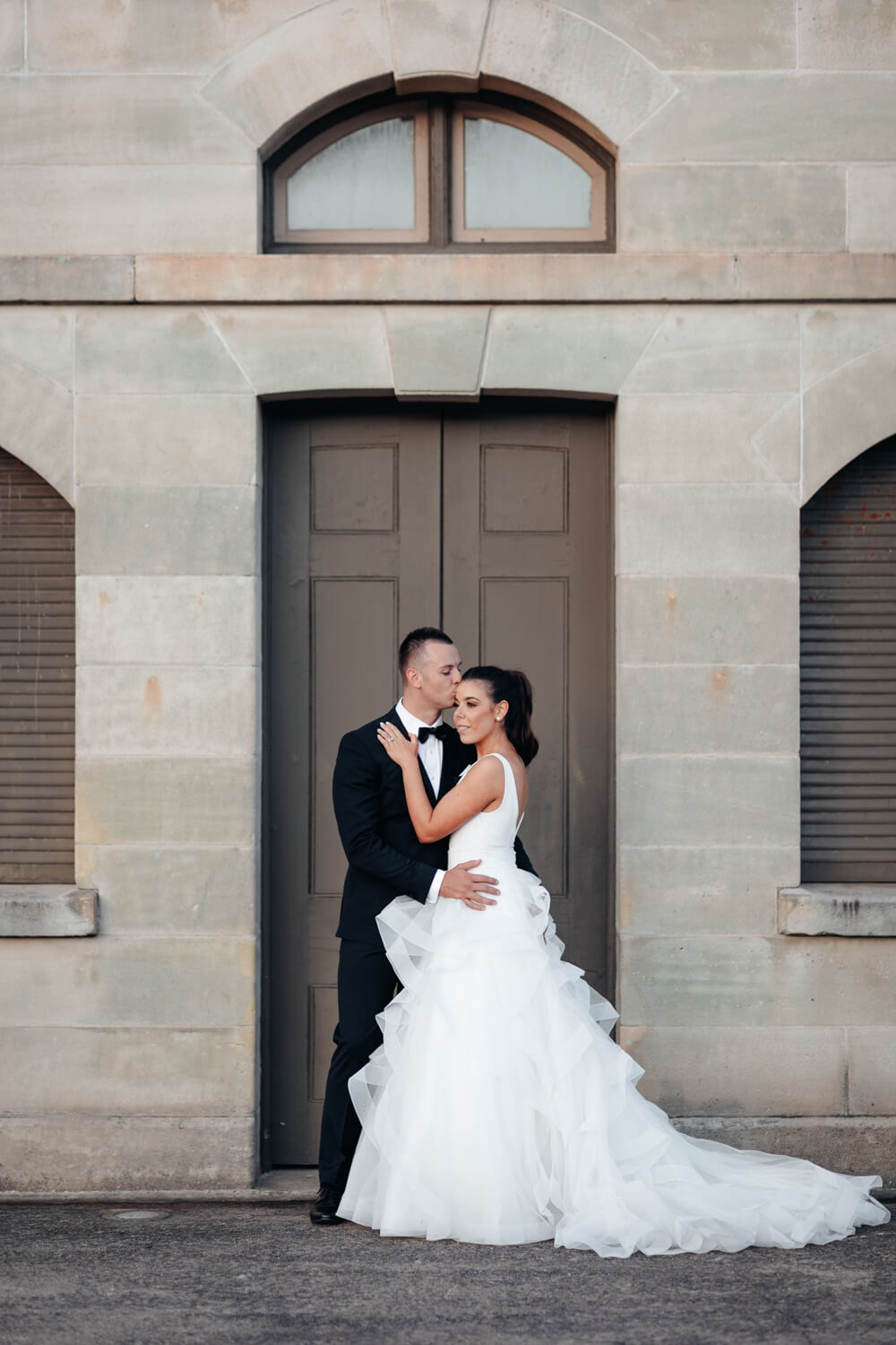Bride and groom standing in front of some old buildings at their Sergeants Mess wedding