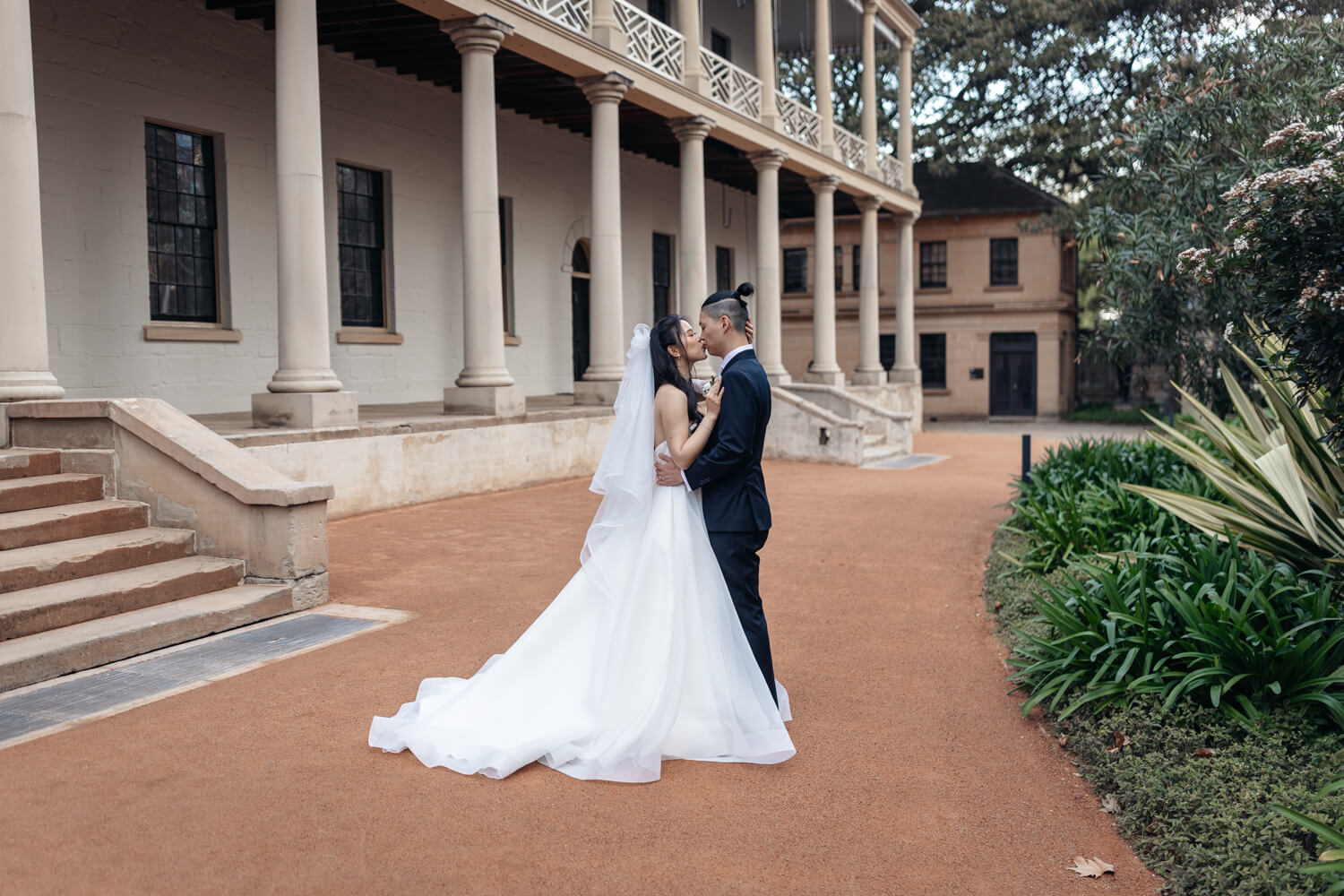 Bride and groom kissing in front of The Mint in Sydney during their wedding