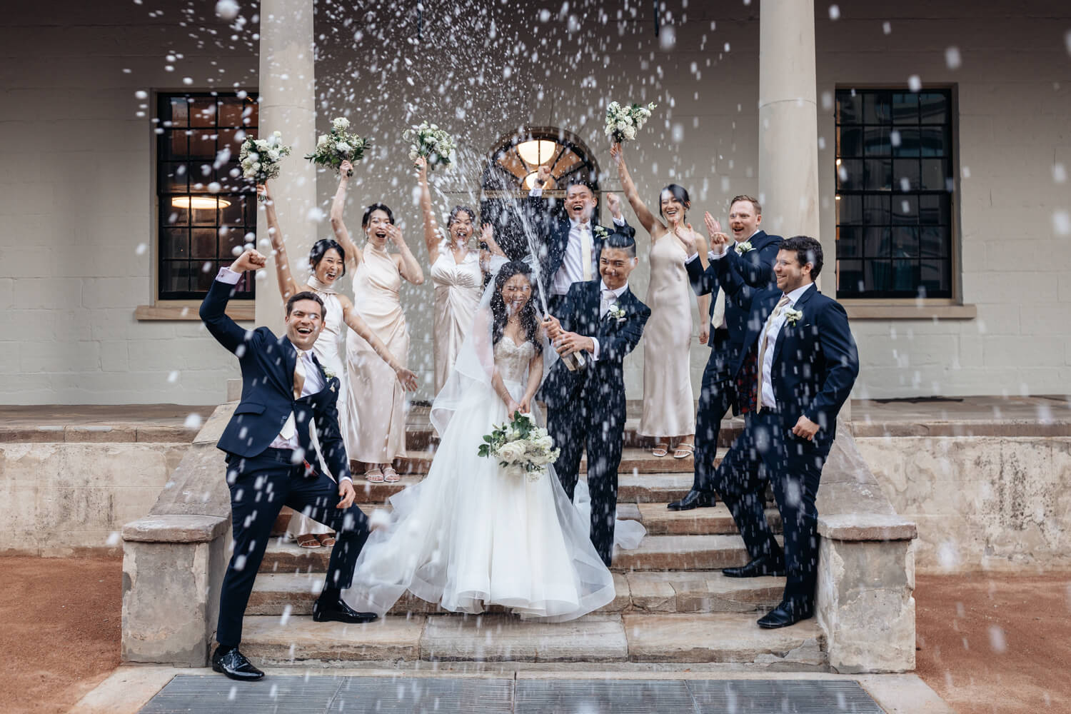 The entire bridal party celebrating with a bottle of champainge at The Mint for their wedding