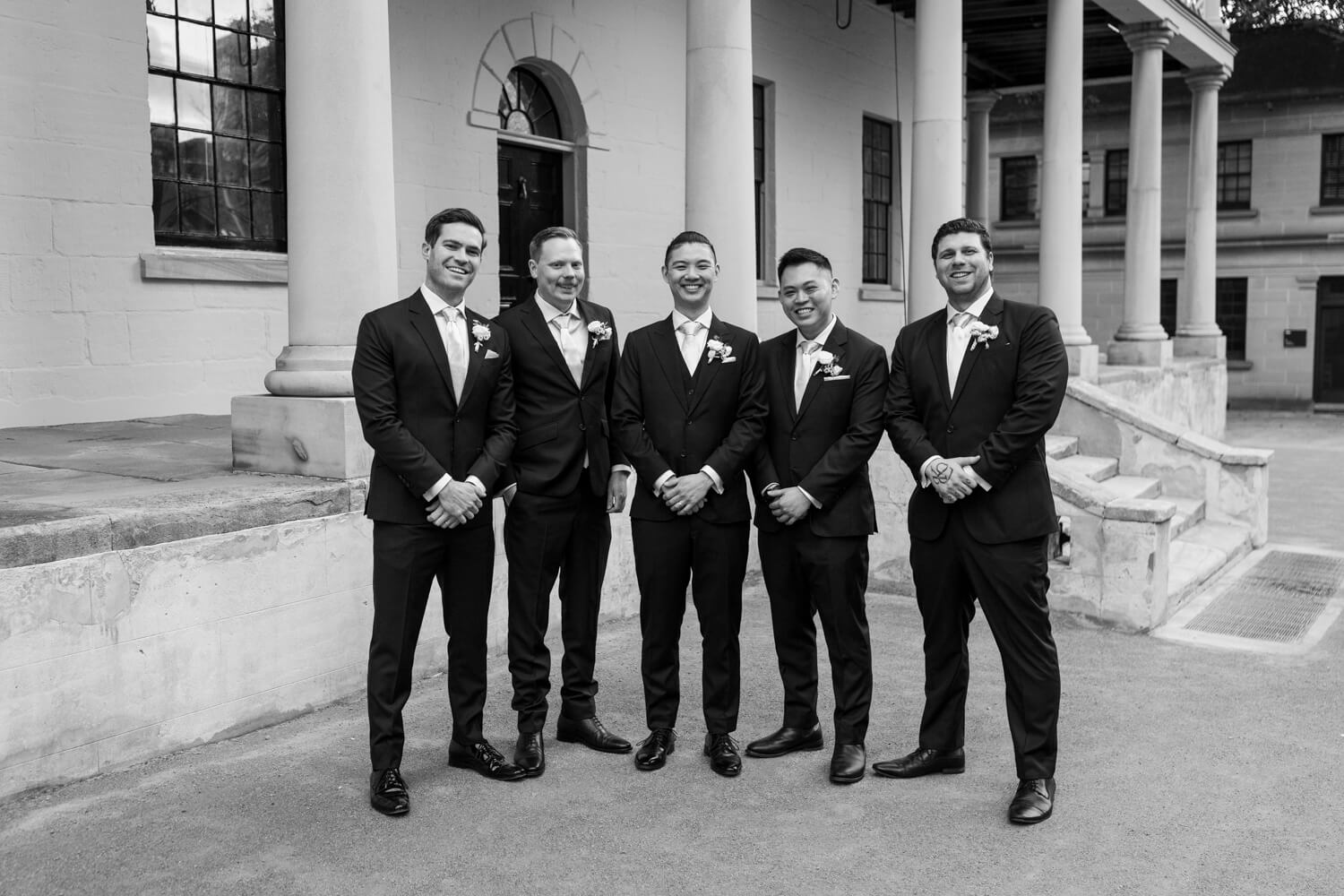 A portrait of the groomsmen standing in front of the mint during their wedding
