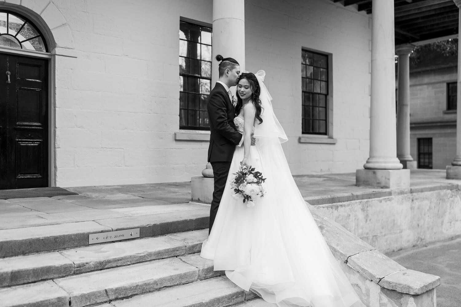 A portrait of the bride and groom standing on the steps together during their wedding at The Mint