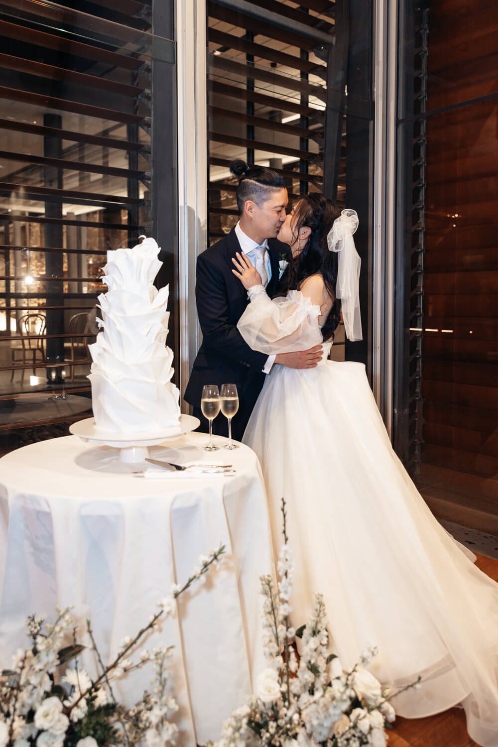 Bride and groom kissing after cutting their wedding cake at The Mint