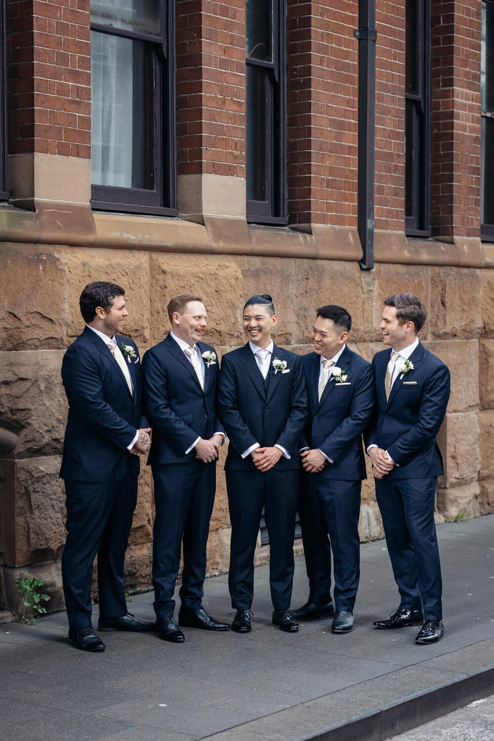Groomsmen smile at each other outside The Old Clare Hotel in Sydney