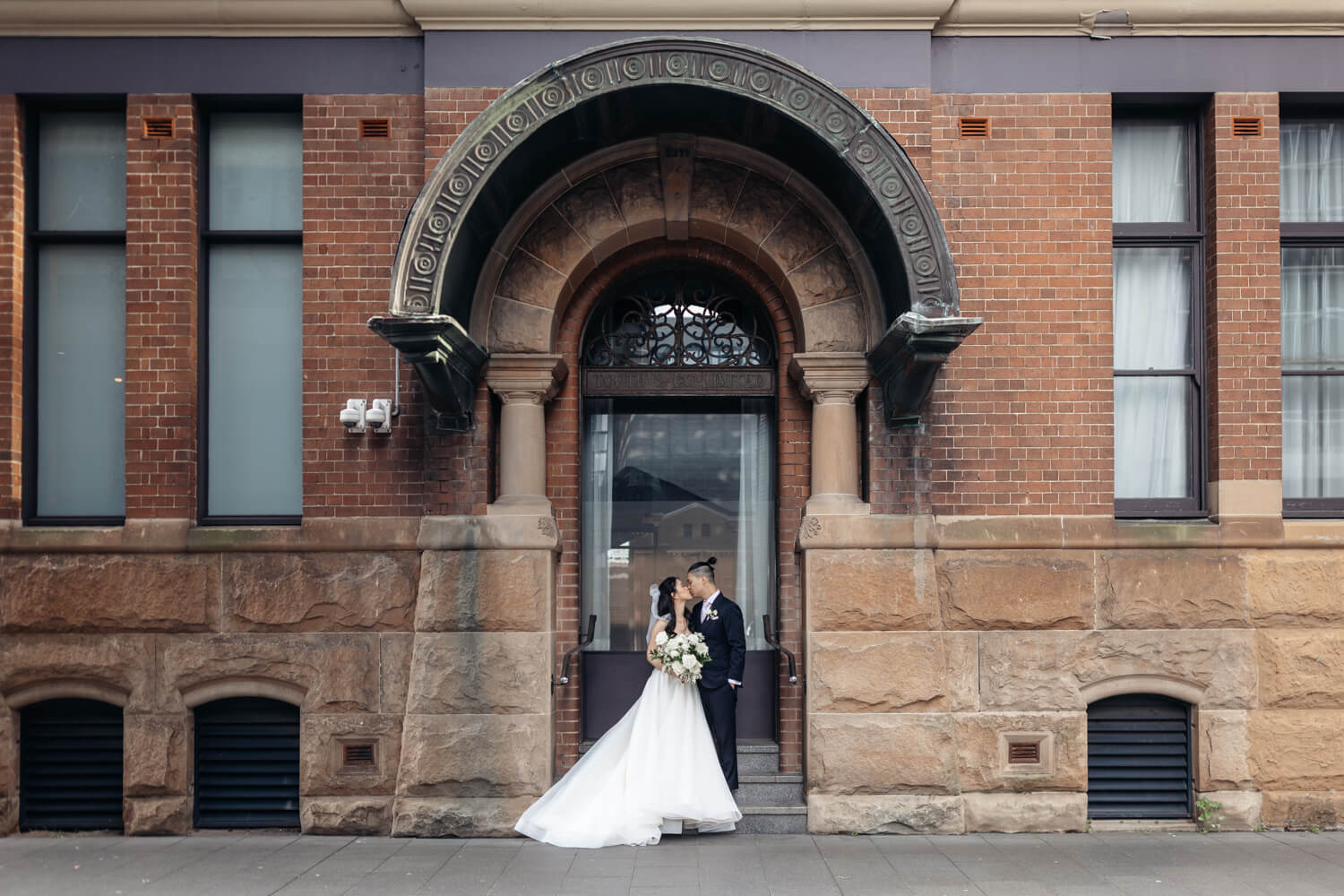 Bride and groom kissing outside The Old Clare Hotel in Sydney