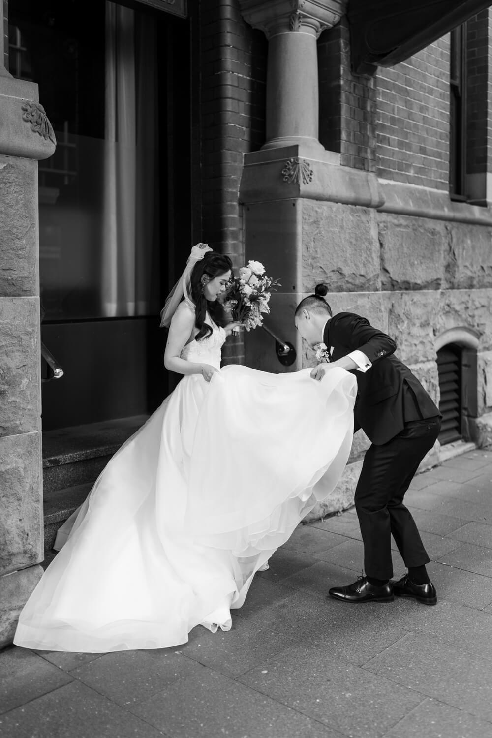 Groom fixes his brides dress at The Old Clare Hotel