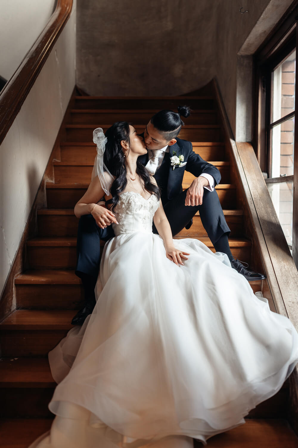 A portrait of the bride and groom kissing on the stairs at The Old Clare Hotel in Sydney