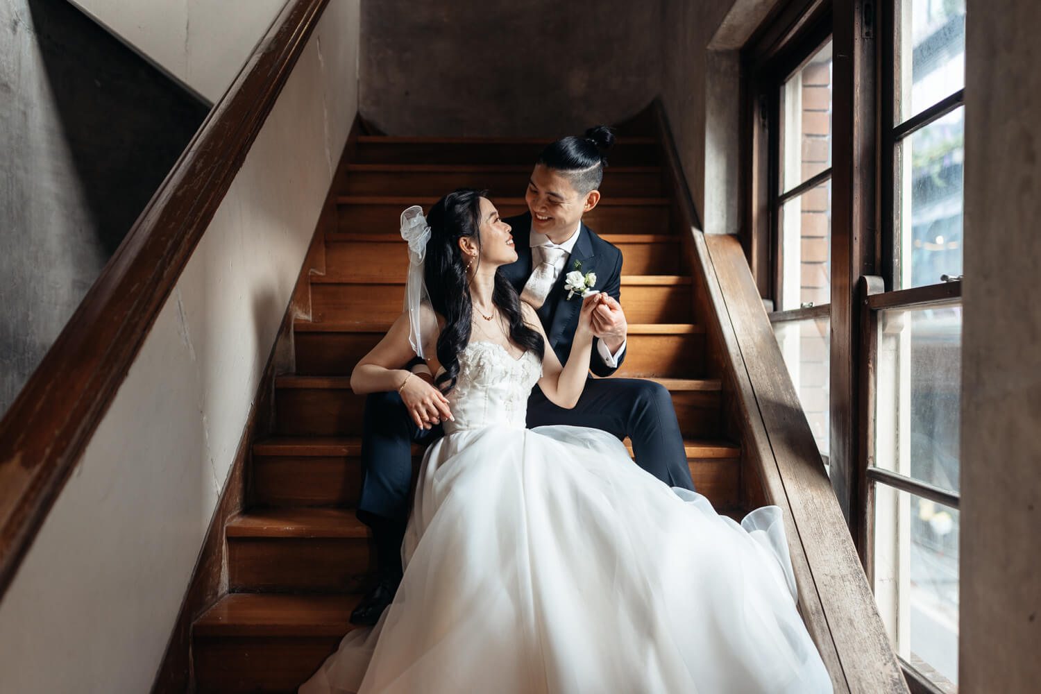 Bride and groom smiling at each other on the stairs at The Old Clare Hotel in Sydney
